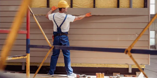 Worker installing siding on a home